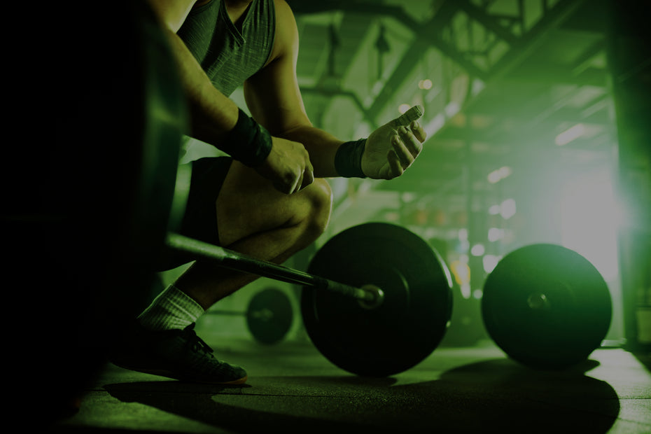 Person preparing to lift a barbell in a gym setting with green lighting